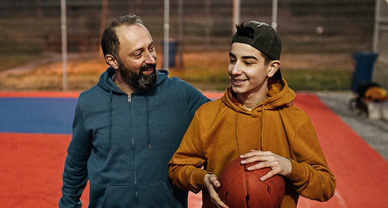father and son at a basketball court, happy and in conversation